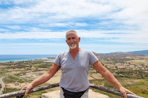 Handsome middle aged man with white hair and beard on vacation posing in fr.. Stock Photos