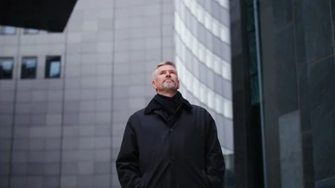 A handsome middle aged old man standing in front of office buildings downtown. Video stock 165204386