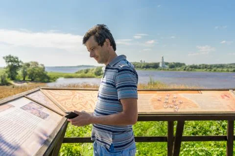Handsome middle-aged tourist man standing near informational board and explor Stock Photos
