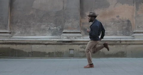Handsome millennial male person dancing while walking along old city street Stock Footage