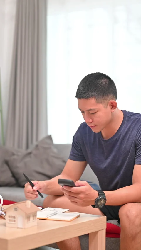 Handsome millennial man using smart phone for making online payments, managing Stock Footage 253406300