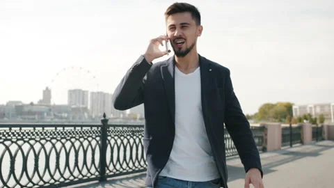 Handsome mixed race guy walking in river embankment and talking on mobile phone Stock Footage 162026458