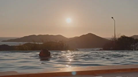 A handsome mixed race man in a view pool, looking at the sunset Stock Footage 313014197