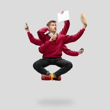 Handsome multi-armed student levitating isolated on grey studio background with Stock Photos