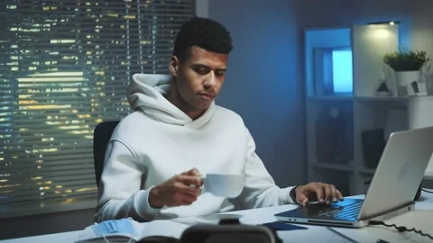 Handsome multiracial man drinking a cup of coffee and working on computer at Stock Footage 131539220