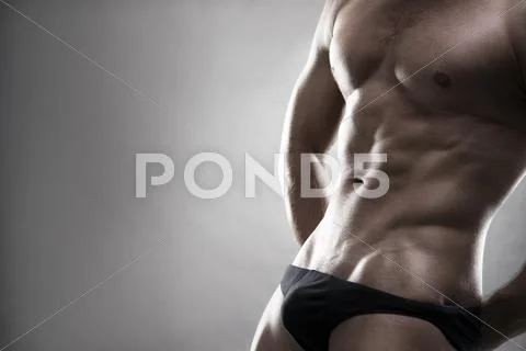 Handsome muscular bodybuilder posing on gray background. Low key stu Stock Photos