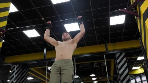 Handsome muscular man boxer pulls himself up in a sports boxing gym. Stock Footage 150344856