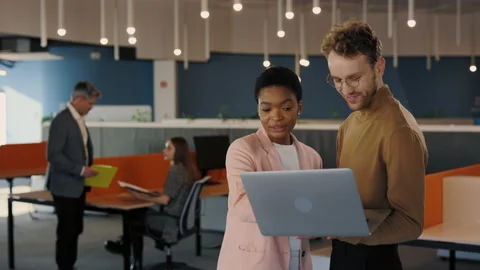 Handsome office worker showing something to his female coworker at the laptop Stock Footage 173438016