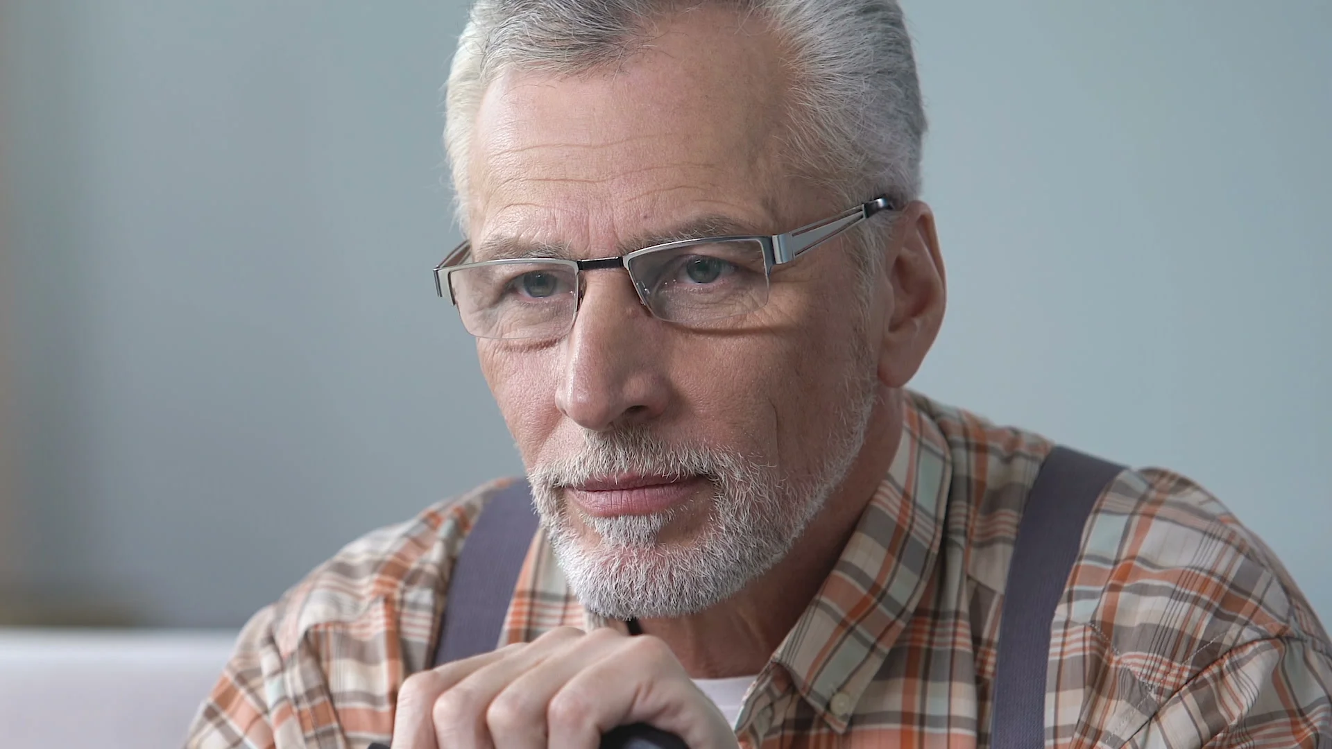 Handsome old man in plaid shirt sighs, happy memories, missing grandchildren