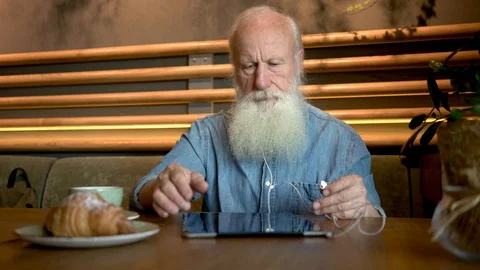 Handsome old man with tablet computer in cafe. 4K Stock Footage 129331884