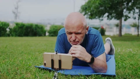 Handsome Old Man Watching Digital Video Content on Smartphone Screen while Lying Stock Footage 148316580