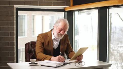 Handsome old man working on digital tablet in home office. Stock Footage 89390784