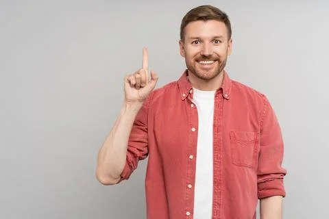 Handsome pleased guy with idea gesture showing direction with finger up for ad Stock Photos