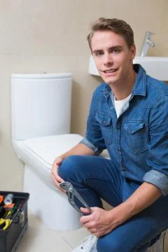 Handsome plumber with toolbox doing toilet reparation Stock Photos