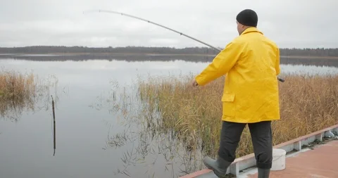 Handsome plus size young man in yellow fisherman coat jacket with fishing rod Stock Footage 103317126