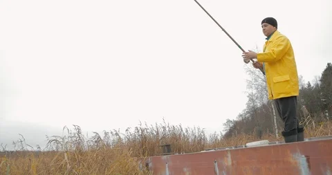 Handsome plus size young man in yellow fisherman coat jacket with fishing rod Stock Footage 103340999