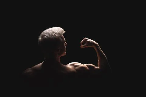 Handsome power athletic man in dramatic light. Strong bodybuilder with perfect Stock Photos