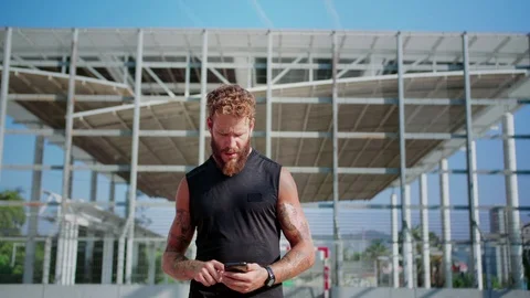 Handsome powerful Caucasian man using sport training application on smartphone Stock Footage 116739768