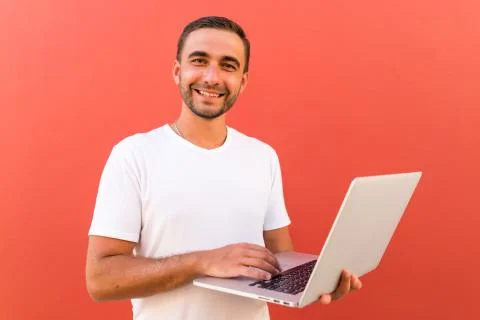 Handsome programmer man with laptop on red background Stock Photos