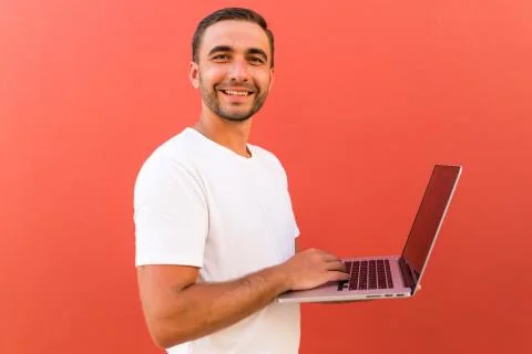 Handsome programmer man with laptop on red background Stock Photos