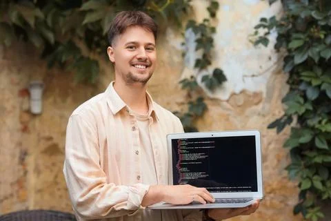 Handsome programmer working with laptop in street cafe Stock-Fotos
