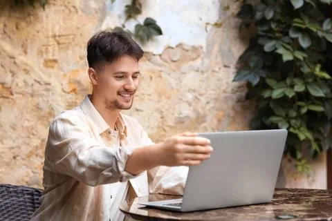 Handsome programmer working with laptop at table in street cafe Stock-Fotos
