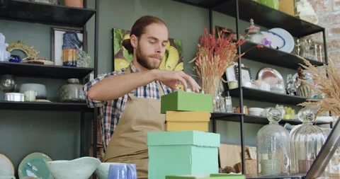 Handsome purposeful young bearded man in casual clothes and apron sitting at Stock Footage 143971936