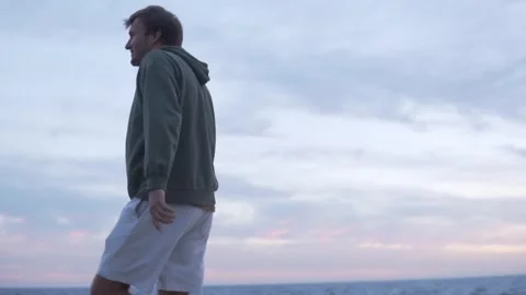 Handsome Russian man walking along the sea in the evening Stock Footage 254297620