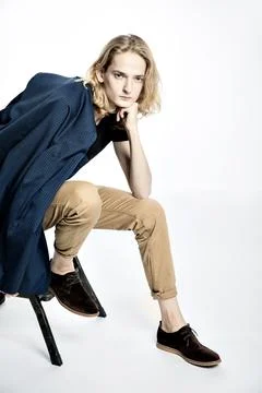 Handsome sad young guy with long blond hair sitting with his head elbows on a Stock Photos