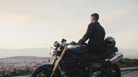 Handsome self-confident popular man and cool new bike enjoying view of Barcelona Stock Footage 102687243