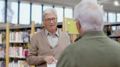Handsome senior man disputing about book with friend in library Stock-Footage 232622217