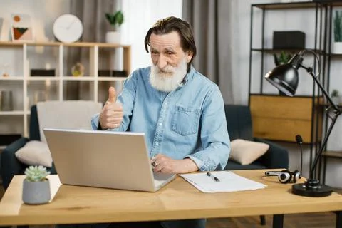 Handsome senior software developer in casual wear typing on laptop while sitting Stock Photos