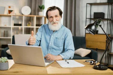 Handsome senior software developer in casual wear typing on laptop while sitting Stock Photos