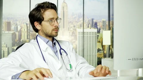 Handsome serious doctor at work on pc in office in city Stock Footage 74752113