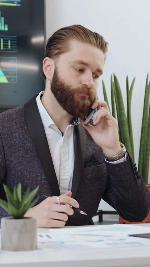 Handsome serious high-skilled confident adult bearded businessman sitting at wor Stock Footage 330799333