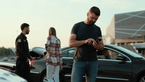 Handsome serious man using a smartphone against policeman and girl. Shocked Stock Footage 112989137