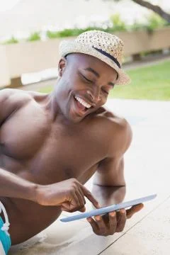 Handsome shirtless man using tablet pc poolside Stock Photos
