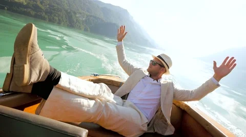 Handsome single man in casual suit enjoying life on boat deck riding over lake Stock Footage 64800985