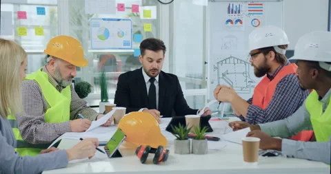 Handsome skilled bearded head chief discussing with his multiracial subordinates Stock Footage 145599233