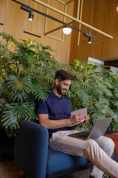 Handsome smiling businessman is making notes during work on laptop in office Stock Photos