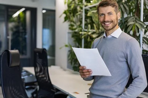 Handsome, smiling businessman with tablet standing in office. Concept of work Stock Photos