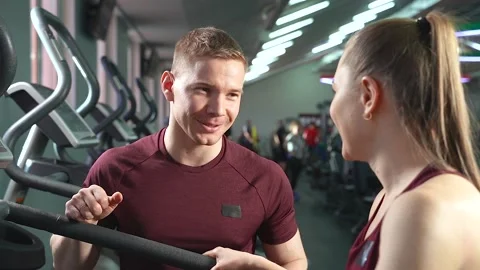 Handsome smiling coach talking to young sporty woman in the gym Stock Footage 101093391