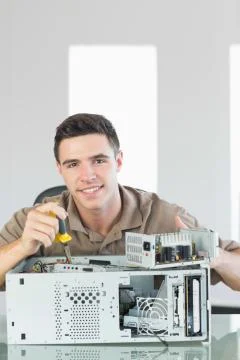 Handsome smiling computer engineer repairing open computer Stock Photos