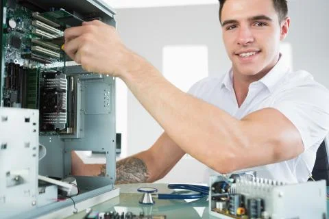 Handsome smiling computer engineer working at open computer Stock Photos