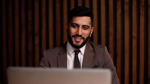 Handsome smiling latin man using laptop computer explaining something having Stock Photos