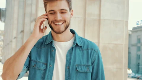 Handsome smiling man in casual clothes while having telephone conversation 库存影片 141037296