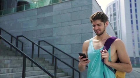 Handsome smiling man in workout clothes with bag walking outside after training Stock Footage 65380772