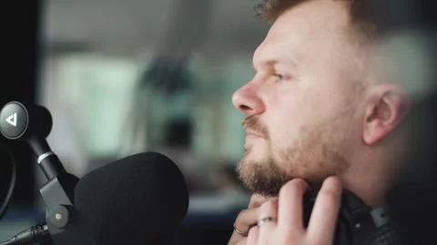 Handsome smiling radio host working in studio with microphone and headphones. Vidéo 240700536