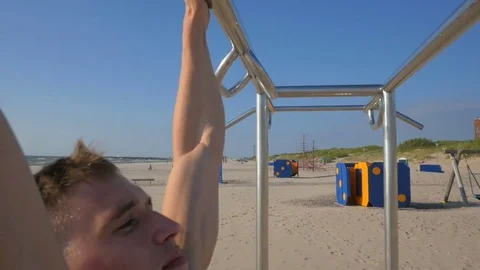 Handsome strong bodybuilder at the beach doing pull ups, side view Video stock 84041829