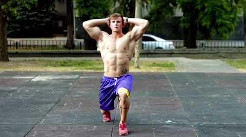 Handsome strong muscular guy working out at the park in the morning. Lunges. Stock Footage 51374554